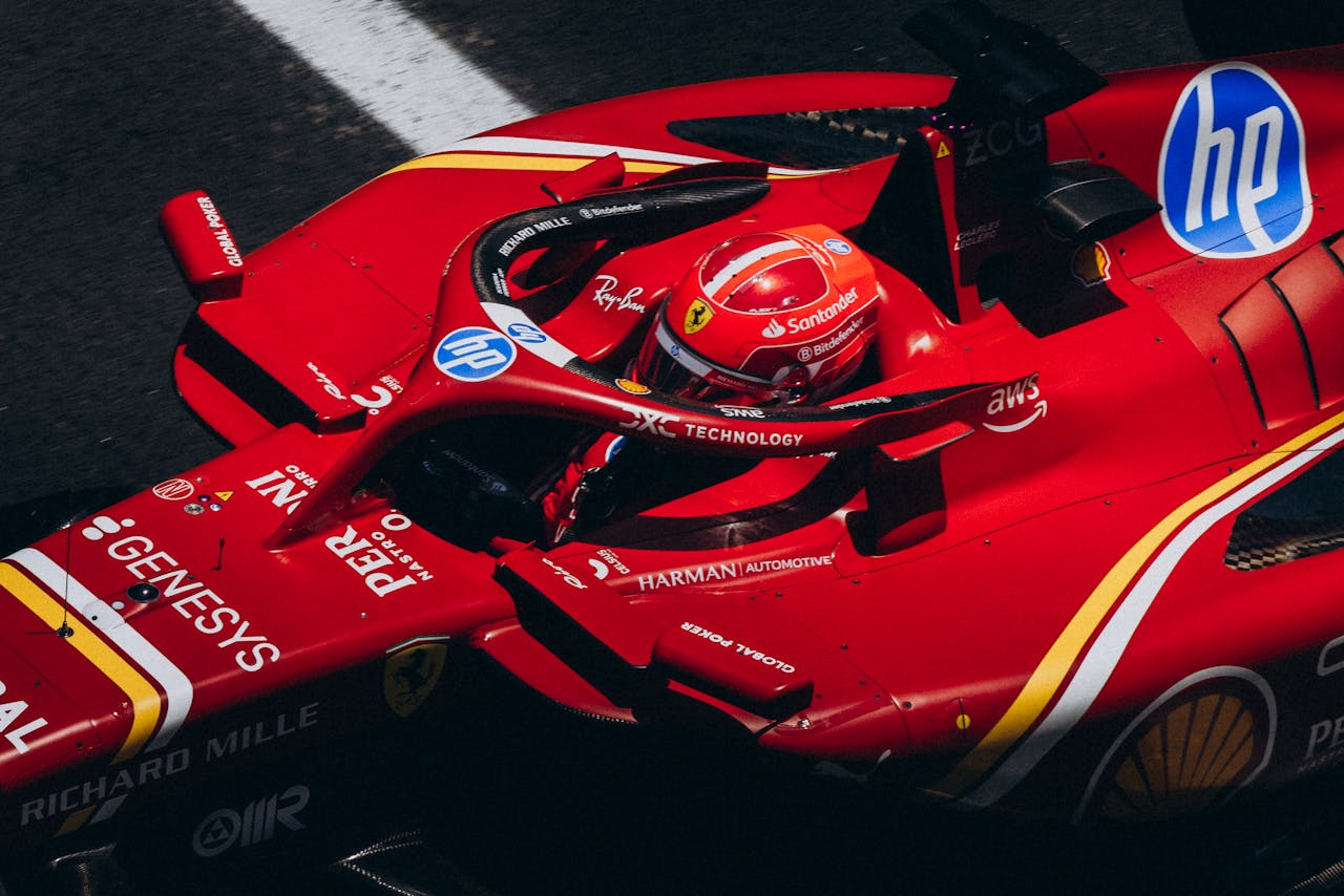 High-speed red racing car zooming down the track, showcasing logos and driver focus.